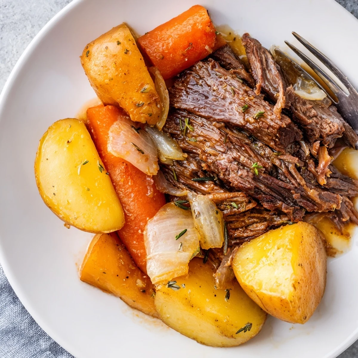 Tender Slow Cooker Pot Roast with carrots and potatoes, swimming in rich beef broth.