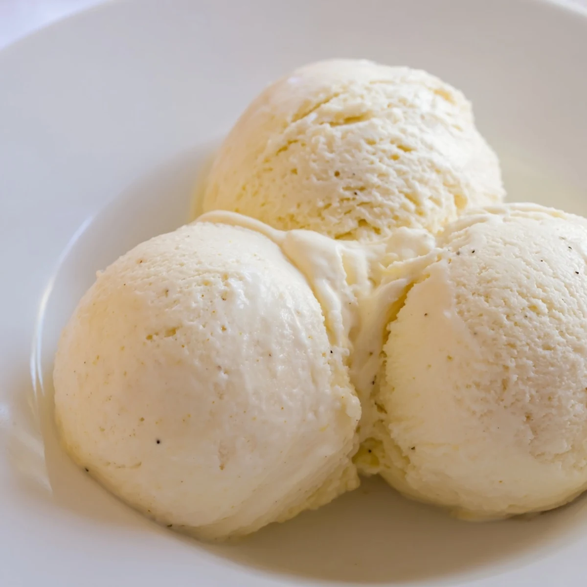 Creamy Treat Ice Cream scoops into a bowl with vanilla bean specks, drizzled with caramel sauce.