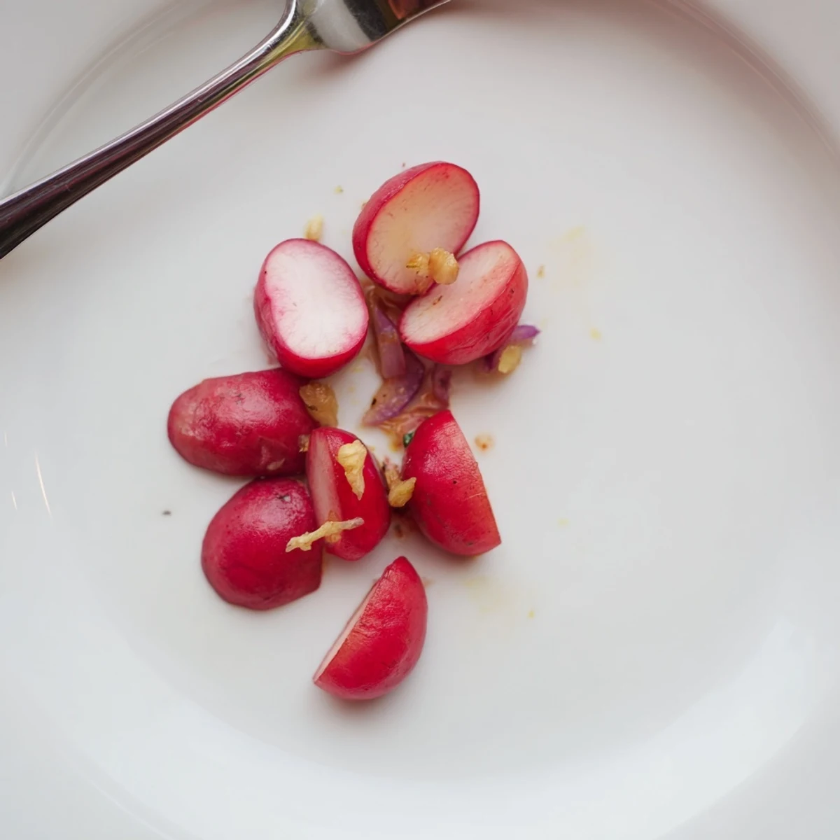 Roasted radishes with garlic and thyme, lightly browned and arranged on a white ceramic dish.