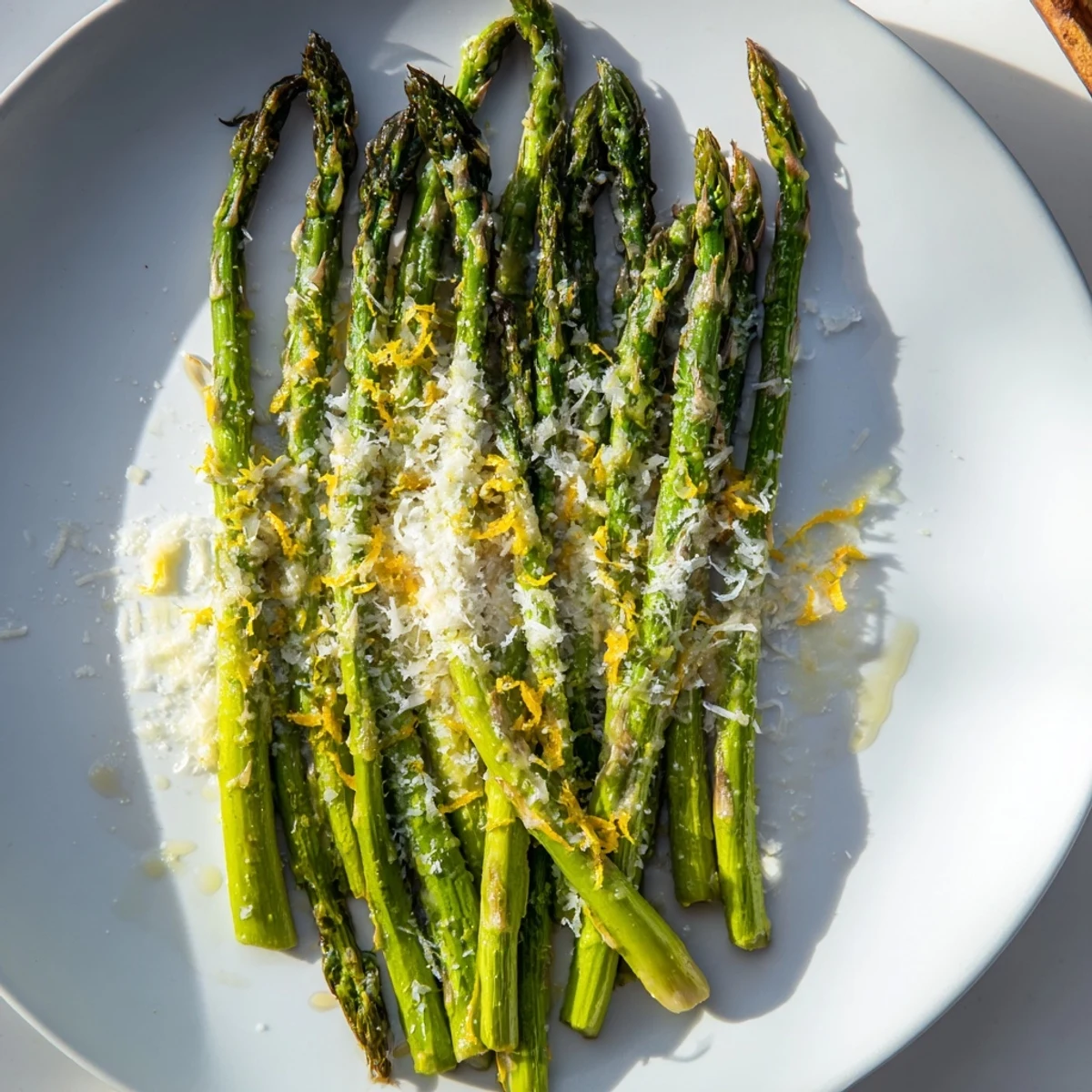 Fresh roasted asparagus with Parmesan and lemon is served warm on a white plate, garnished with extra zest.