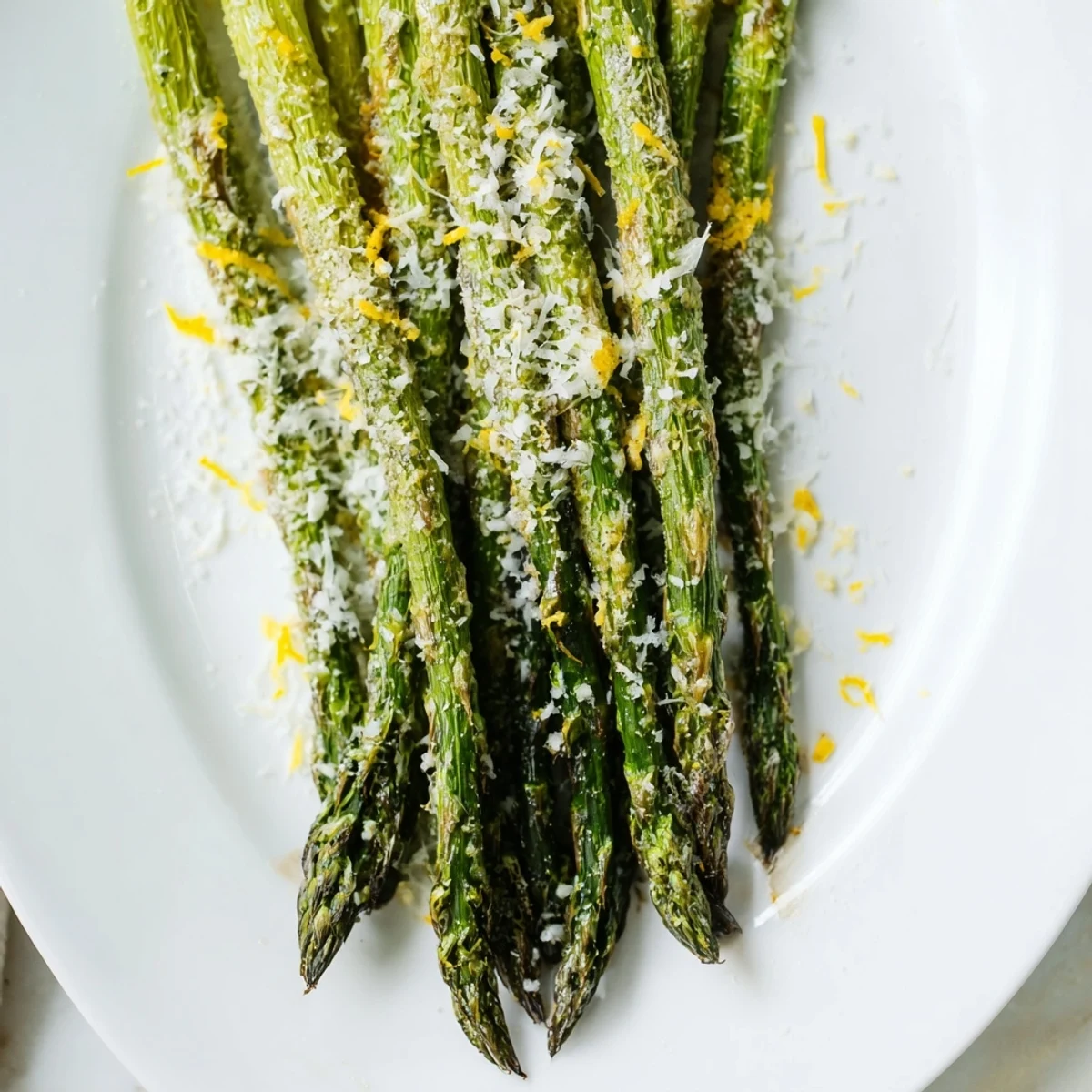Roasted asparagus with Parmesan and lemon drizzled with olive oil, paired with grilled chicken on a dinner plate.