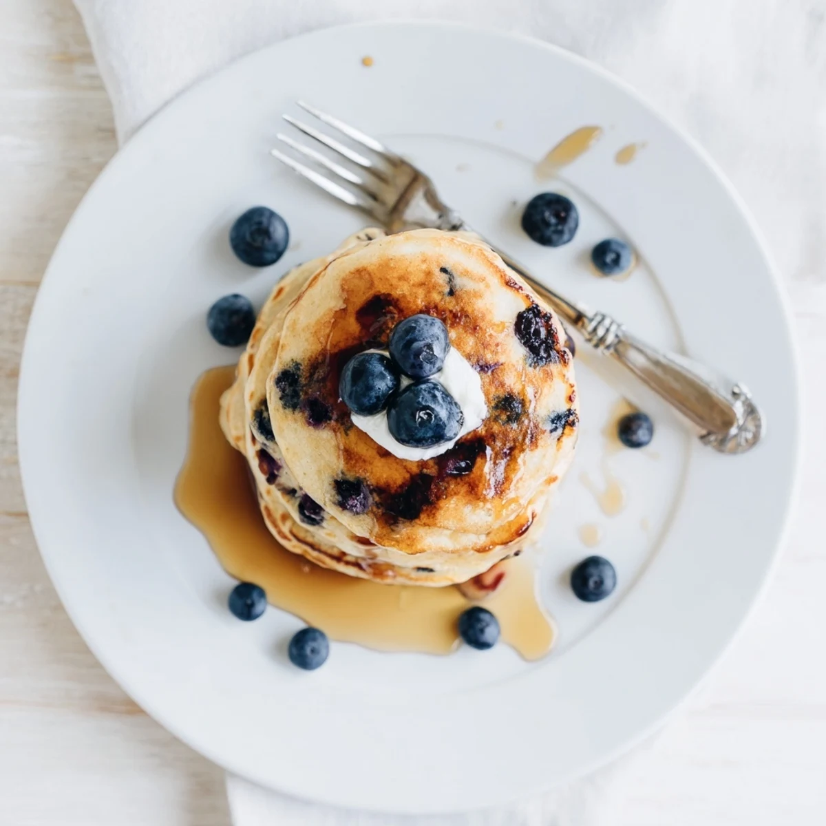 Golden-brown Fluffy Greek Yogurt Blueberry Pancakes sizzling on a griddle with visible berries.  