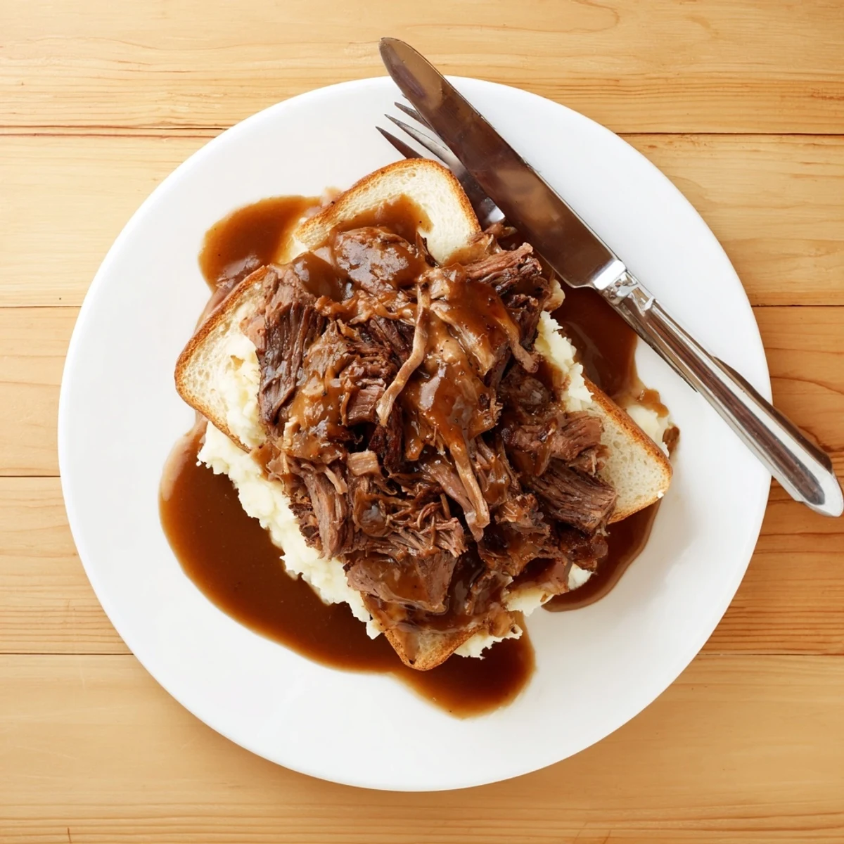 Tender shredded Slow Cooker Beef Manhattan piled on thick bread with creamy mashed potatoes and rich brown gravy, a cozy Midwestern meal.