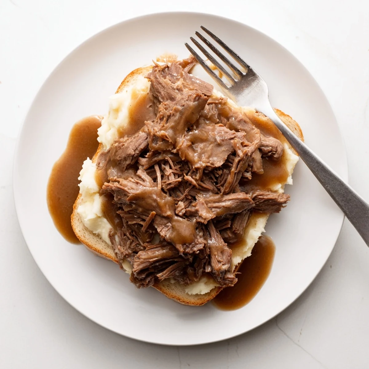 Savory Slow Cooker Beef Manhattan served over Texas toast, loaded with tender shredded beef, mashed potatoes, and ladled with rich brown gravy.