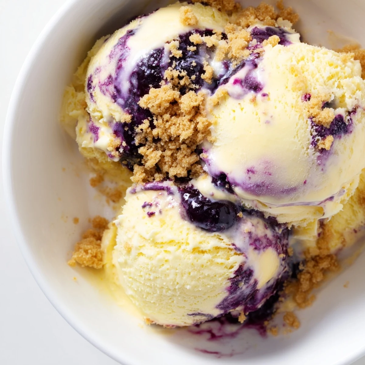 A chilled pint of Lemon Blueberry Cheesecake Ice Cream features a rich blueberry swirl and creamy cheesecake texture.