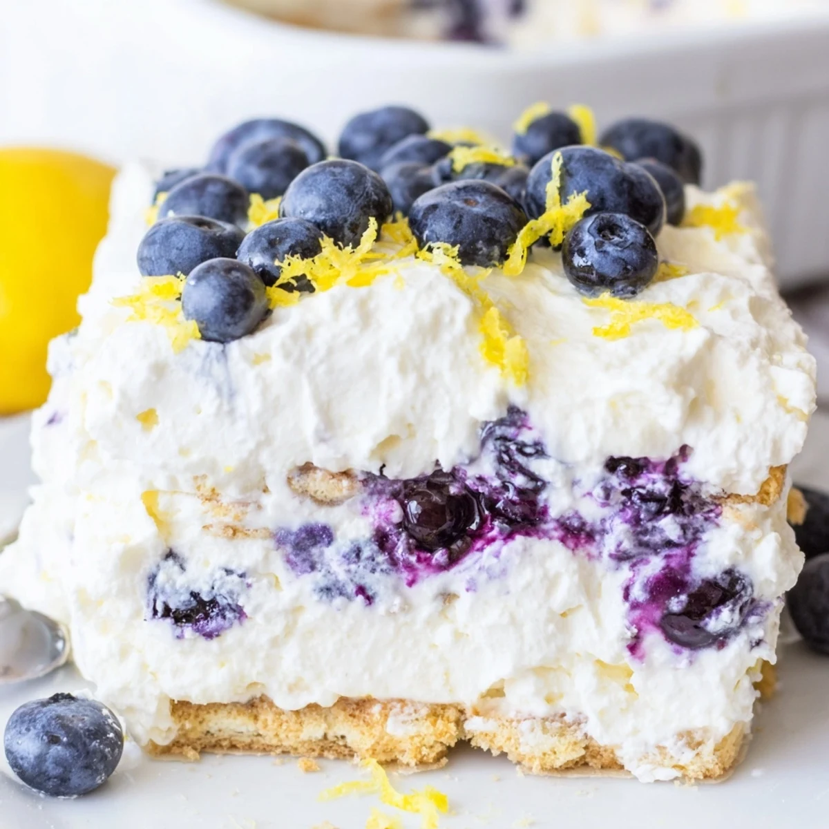 Creamy no bake lemon blueberry cake topped with fresh blueberries and lemon zest on a graham cracker crust