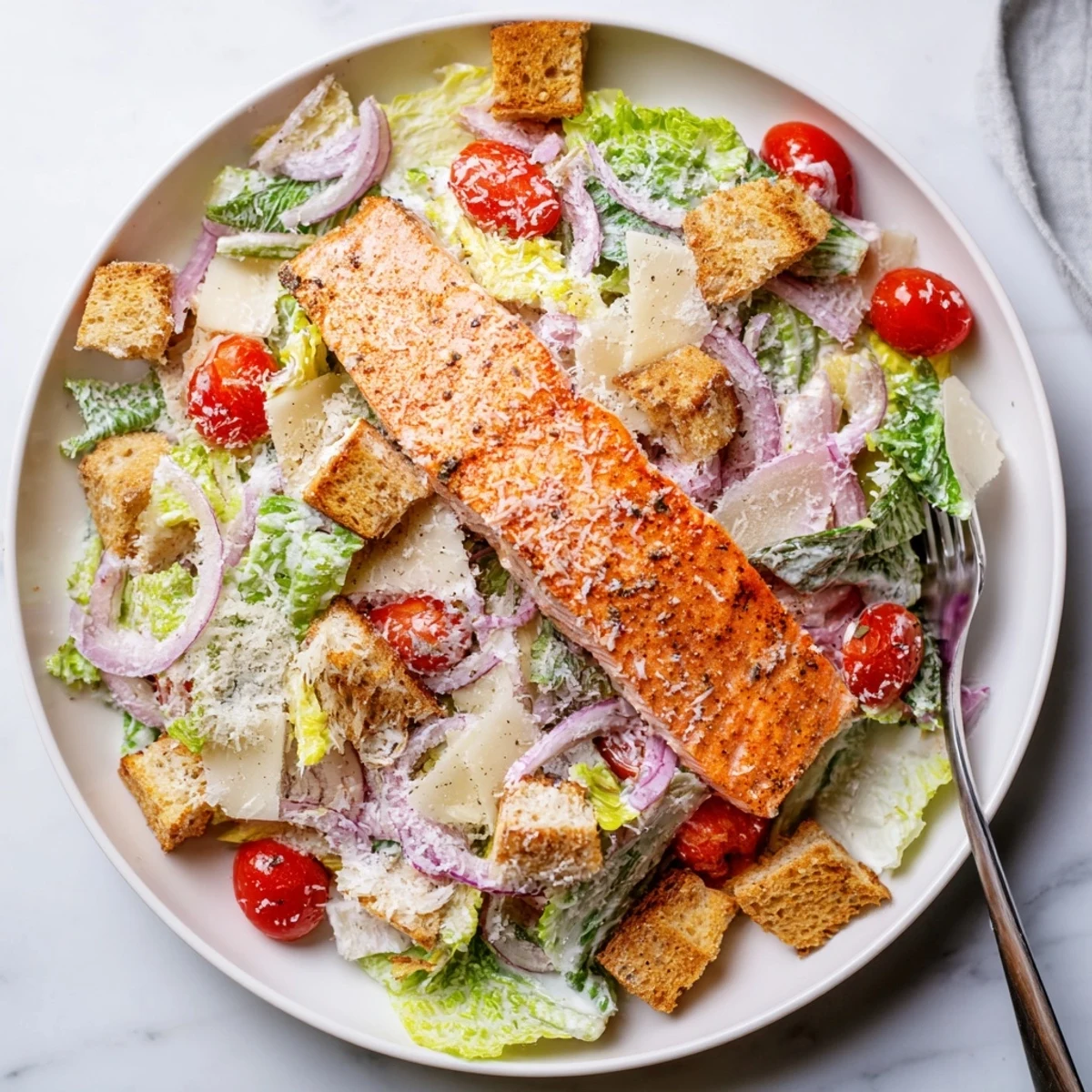 Golden grilled salmon fillet resting atop crisp romaine Caesar salad with crunchy croutons and shaved Parmesan