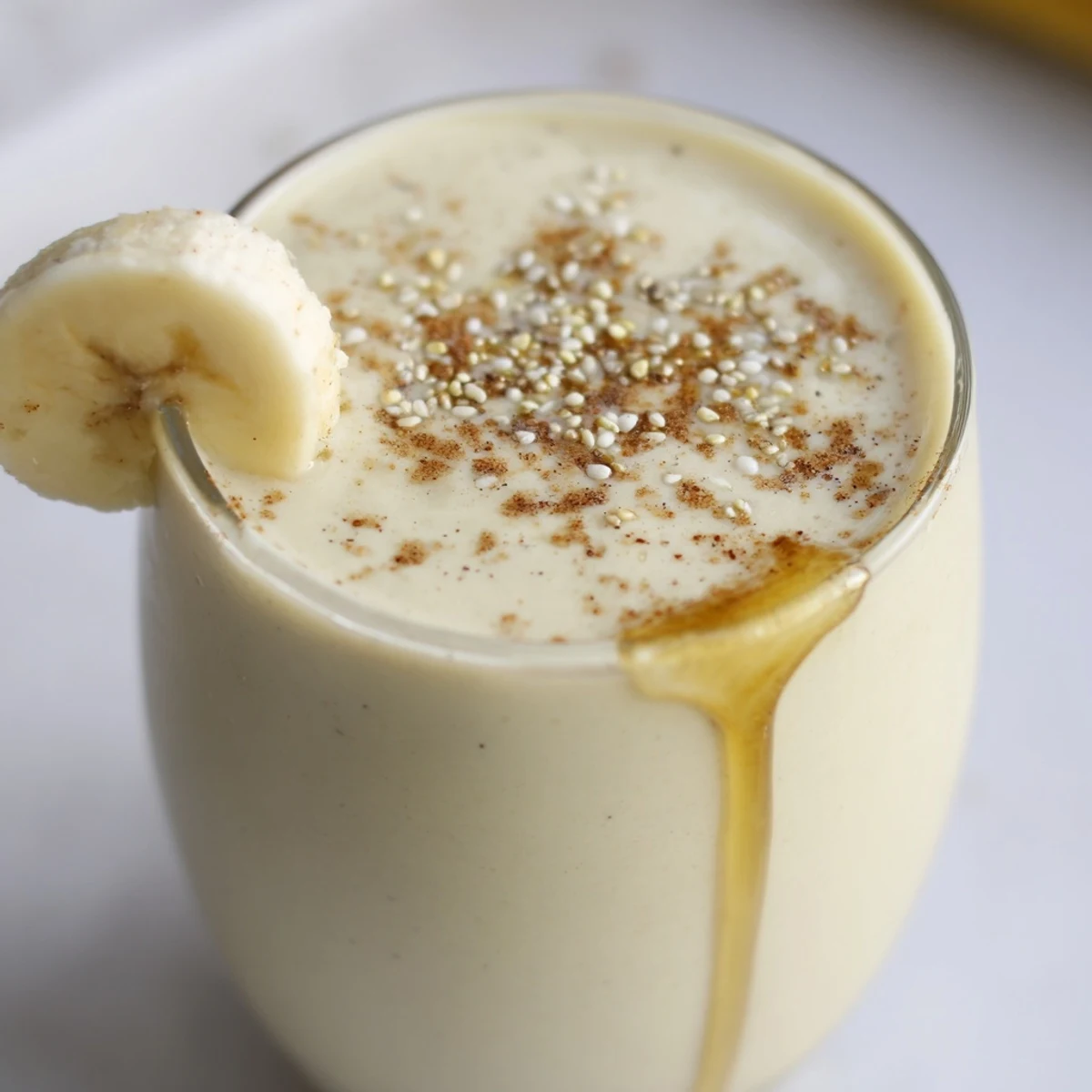 Thick golden banana smoothie blended with protein-rich Greek yogurt and garnished with cinnamon