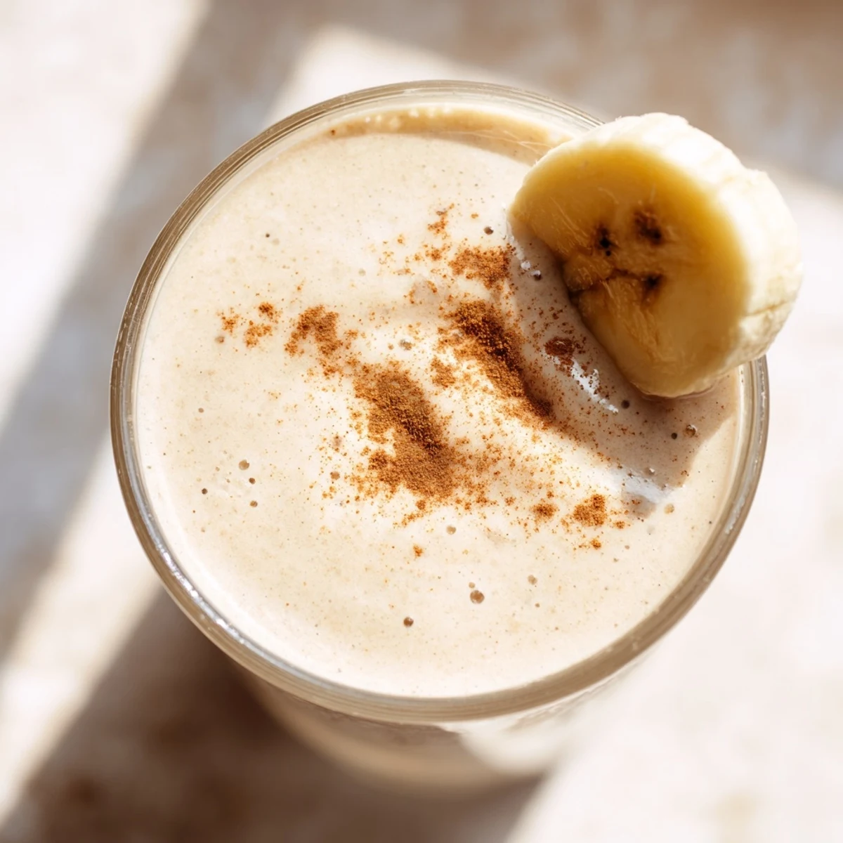 Vibrant Greek yogurt banana smoothie garnished with cinnamon and honey in a clear serving glass