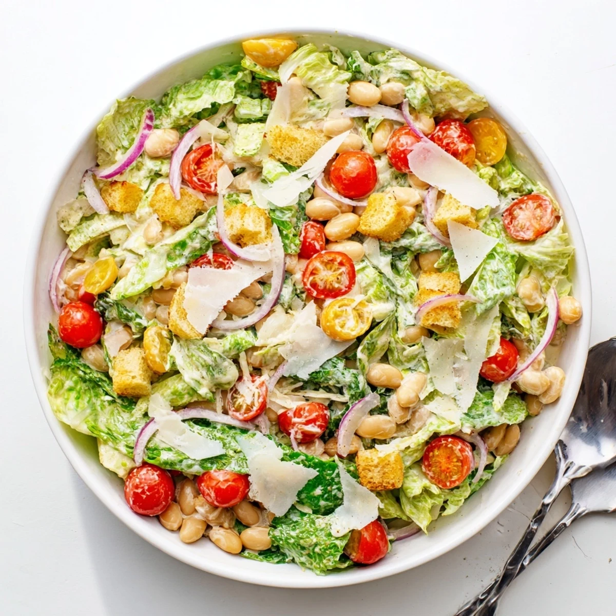 Fresh protein-rich butter bean Caesar salad topped with tangy homemade dressing and cherry tomatoes