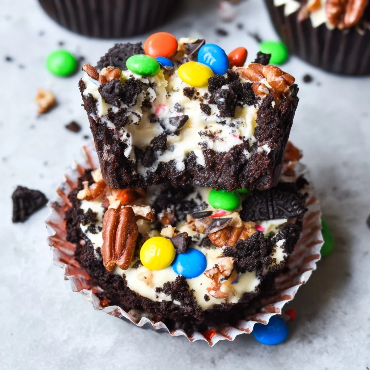 Decadent loaded brownie cheesecake cups sprinkled with nuts and mini chocolate candies