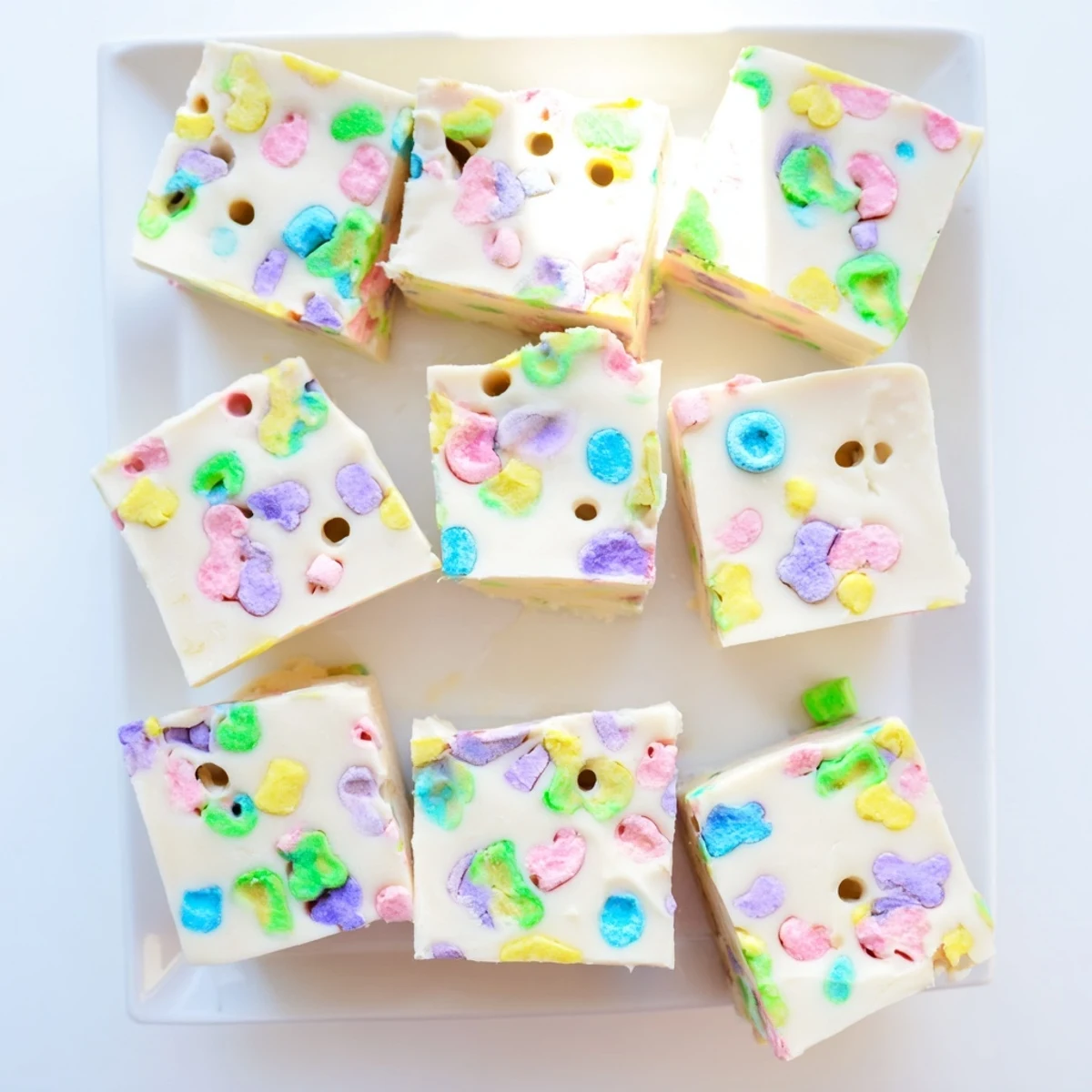Creamy Easy Lucky Charms Fudge squares topped with colorful marshmallows on a white plate