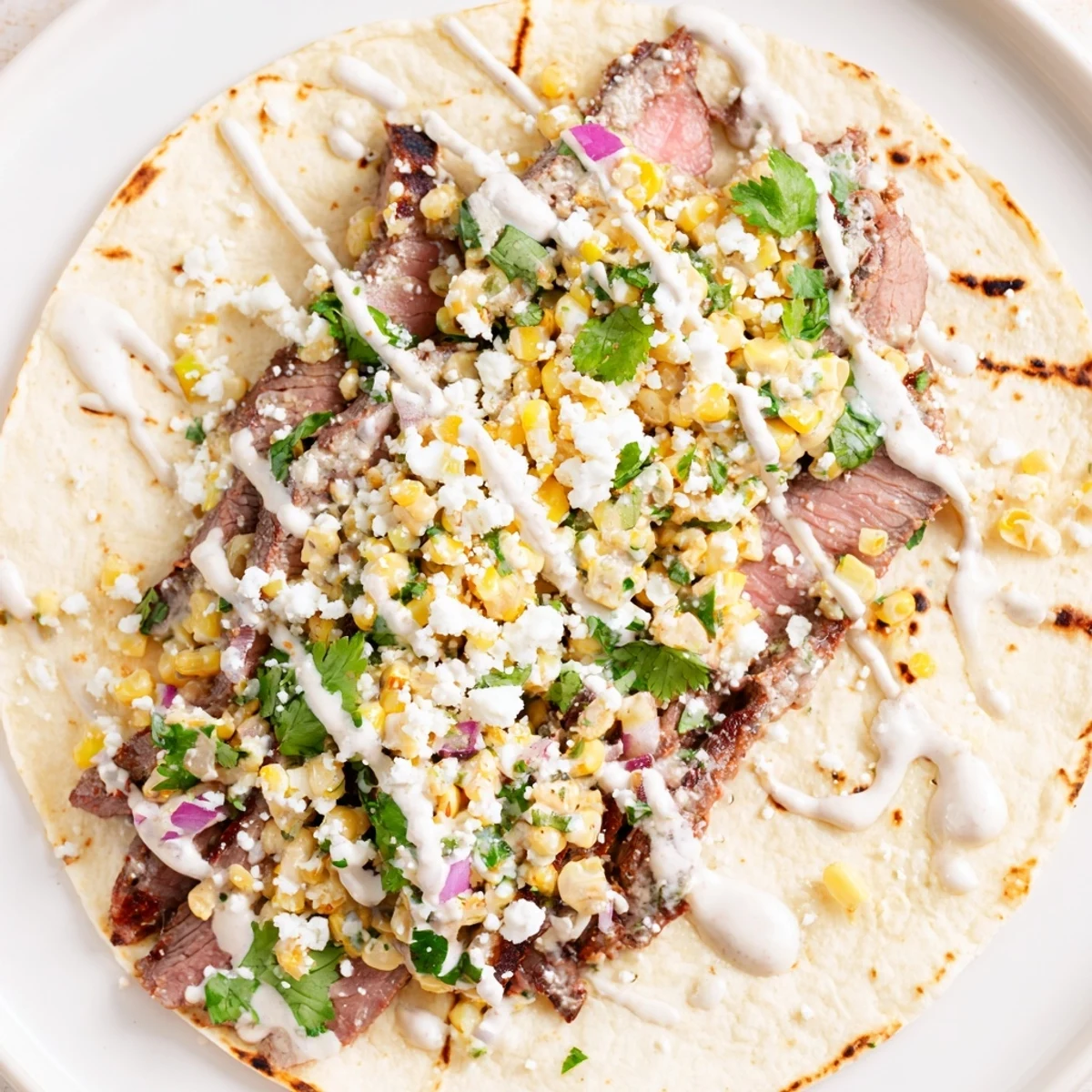 Warm corn tortillas filled with smoky grilled steak and zesty elote corn mixture with lime