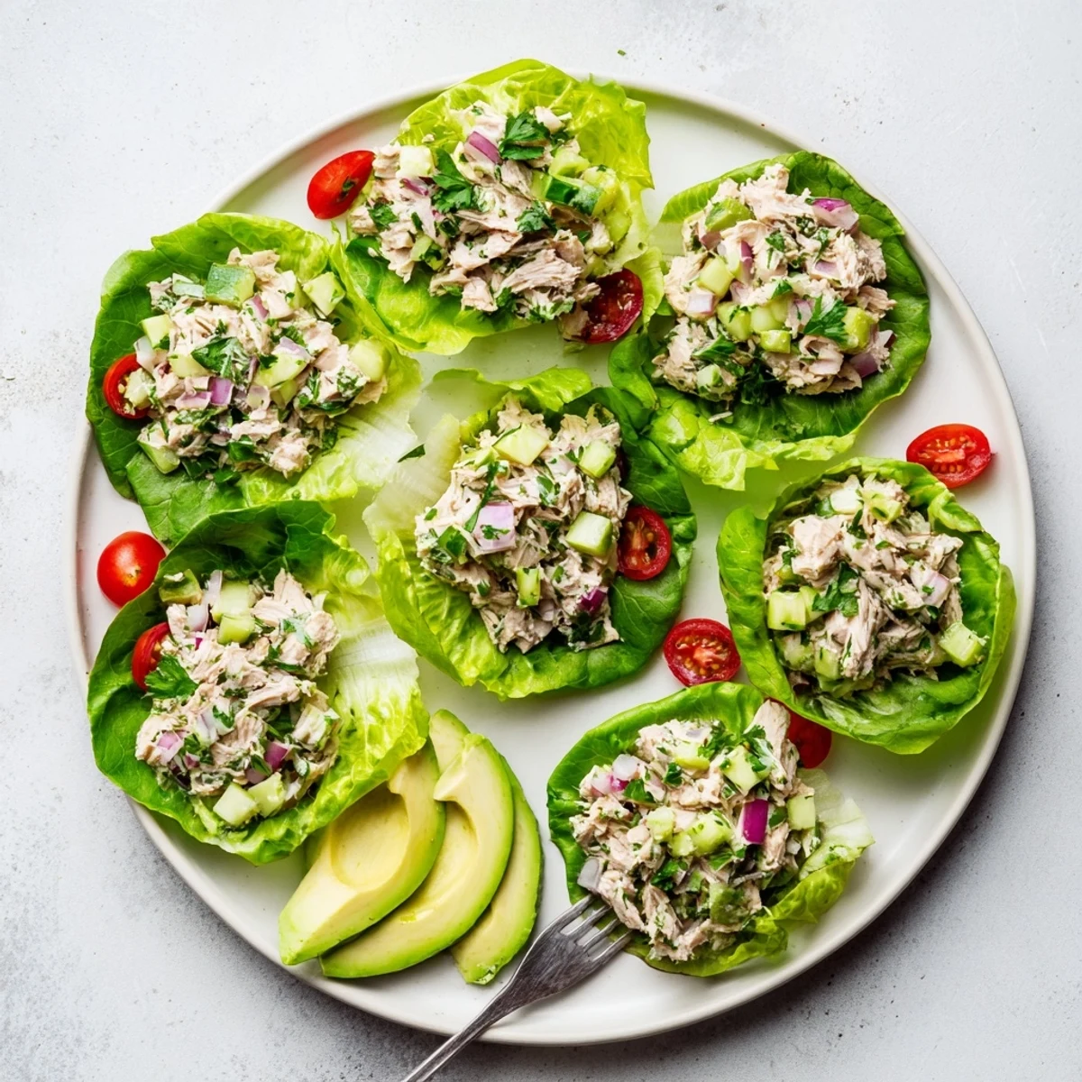 Crisp lettuce cups overflowing with zesty tuna salad, fresh vegetables, and creamy avocado slices