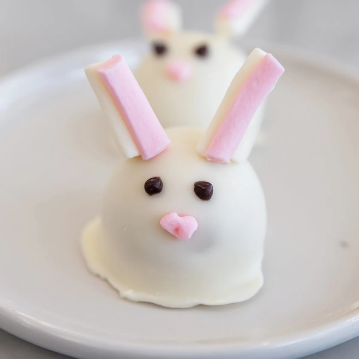 Adorable white chocolate bunny Oreo balls decorated with pink ears and fluffy marshmallow tails