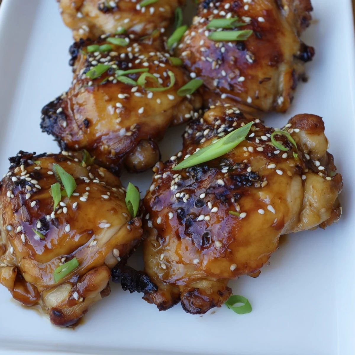 Golden roasted garlic miso chicken thighs garnished with sesame seeds and fresh spring onions