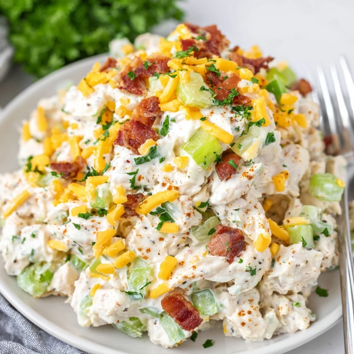 Creamy low carb jalapeno popper cottage cheese chicken salad topped with crispy bacon crumbles and fresh diced jalapeños in a white serving bowl