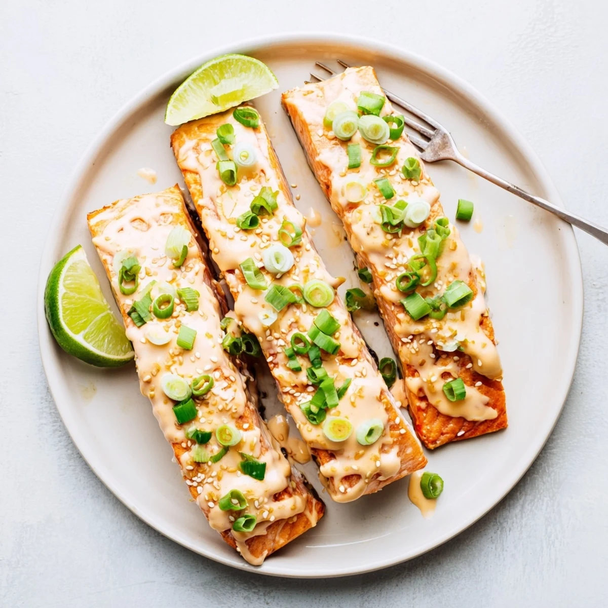 Golden baked Bang Bang salmon fillets glazed with creamy spicy red sauce and sprinkled with fresh green onions