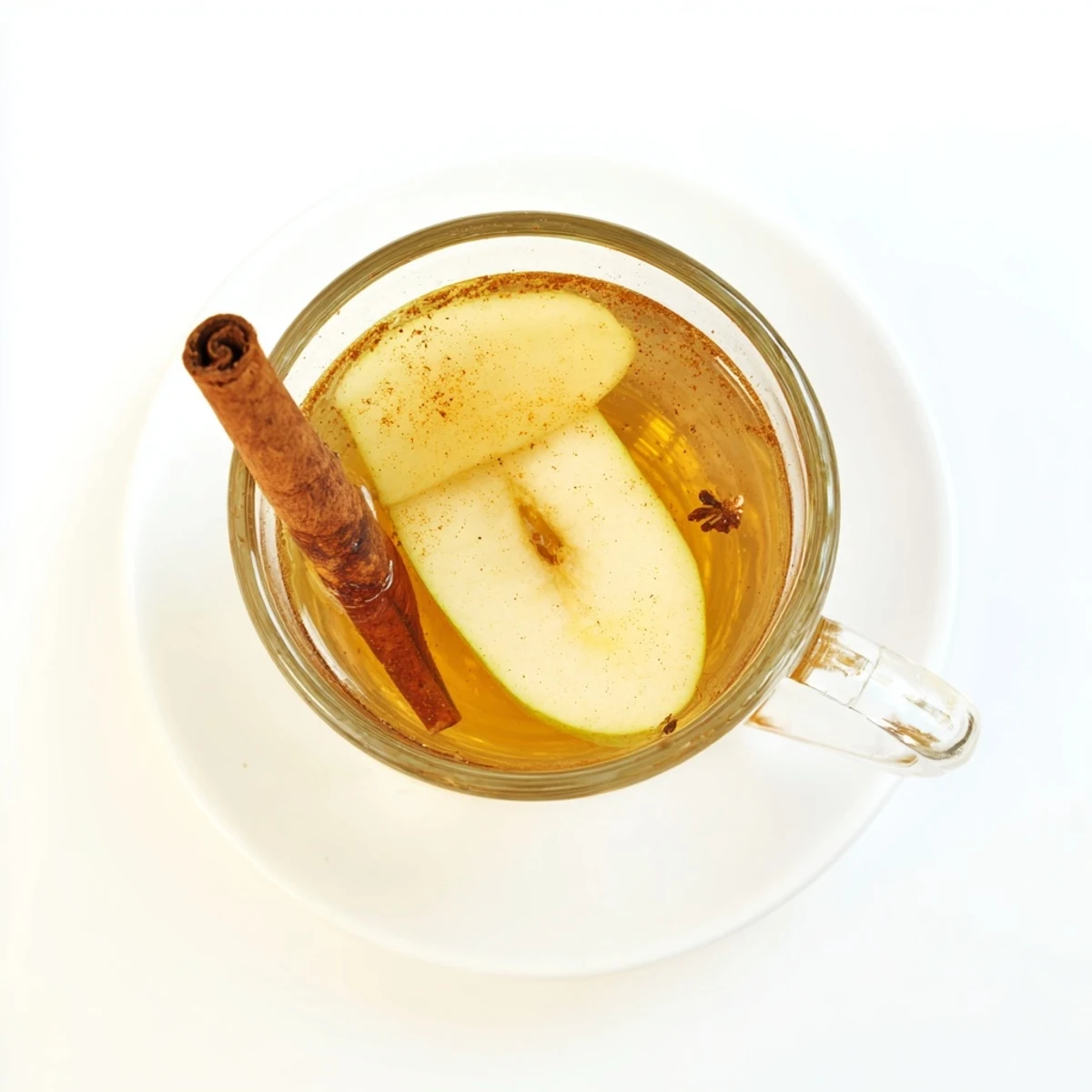 Golden spiced pear cider simmering in copper pot with whole cinnamon sticks and ripe fruit pieces