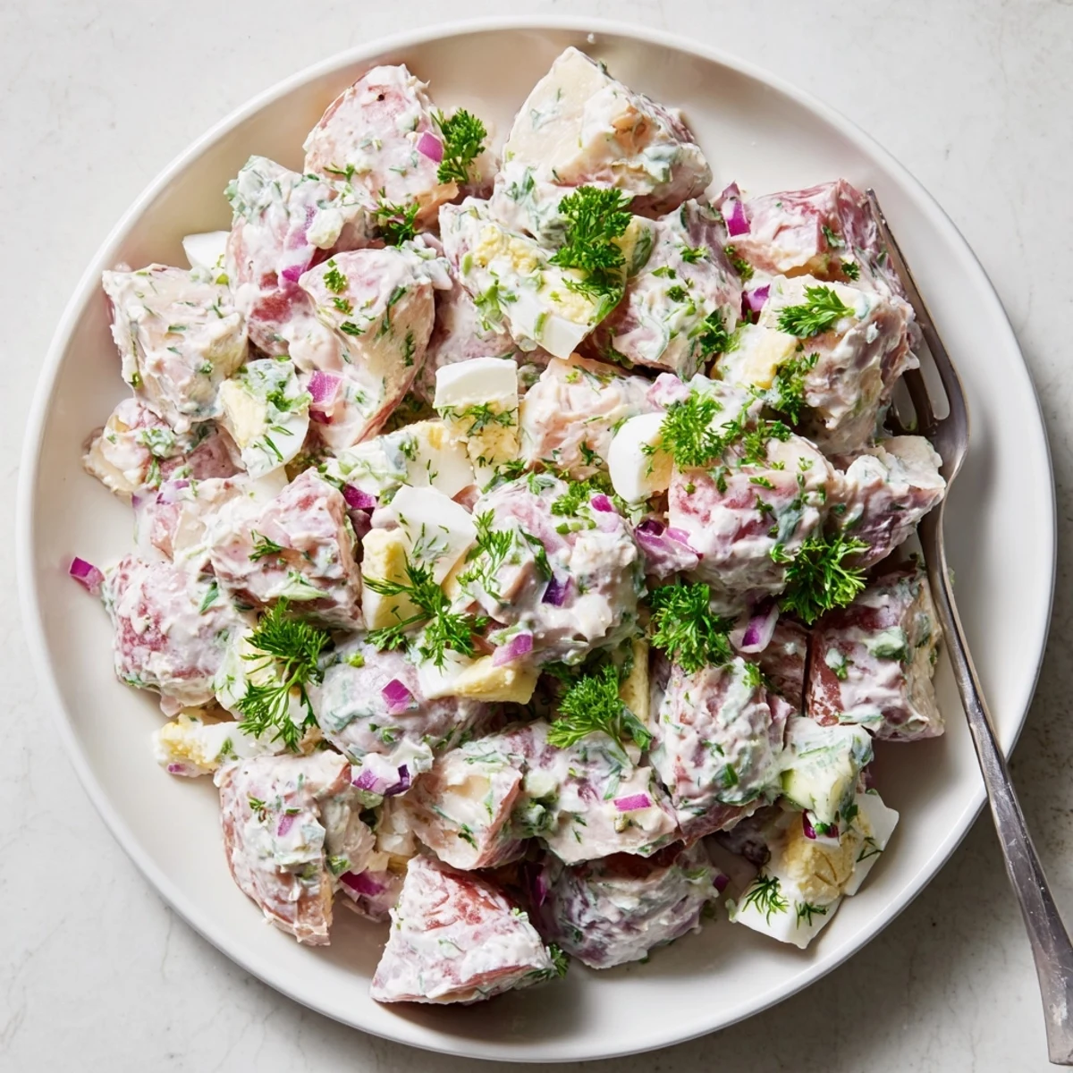 Creamy red potato salad with tender cubes, crisp celery, and fresh herbs in a bowl