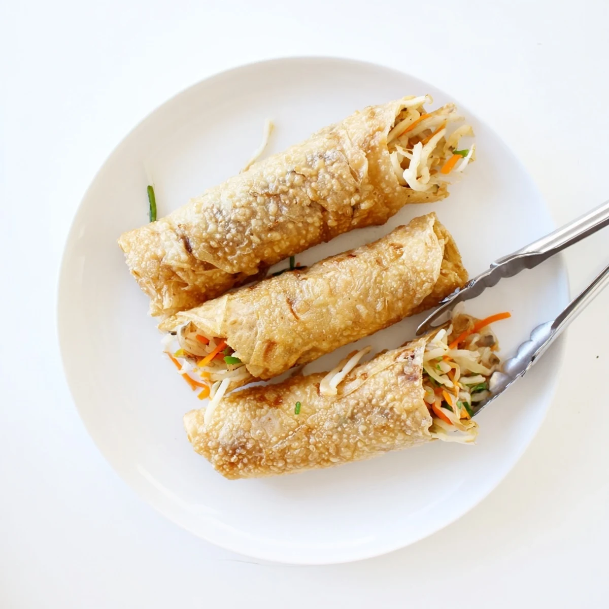 Golden crispy rice paper spring rolls served on white plate with sweet chili dipping sauce