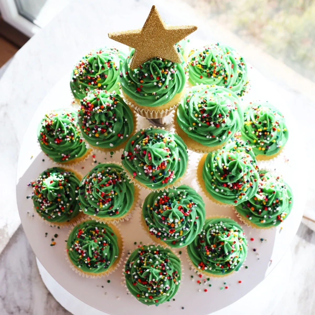 Festive cupcake Christmas tree with green buttercream, colorful sprinkles, and golden star topper
