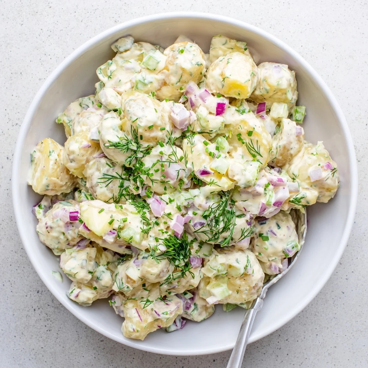 Lightened-up Greek yogurt potato salad with tender potatoes, crunchy vegetables, and vibrant herbs for summer picnics