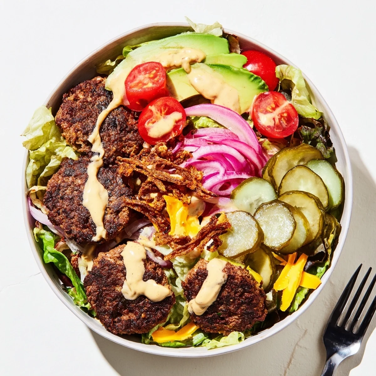 Close-up Smash Burger Bowl salad with savory smashed beef crispy fried onions ripe avocado slices and drizzled homemade burger dressing
