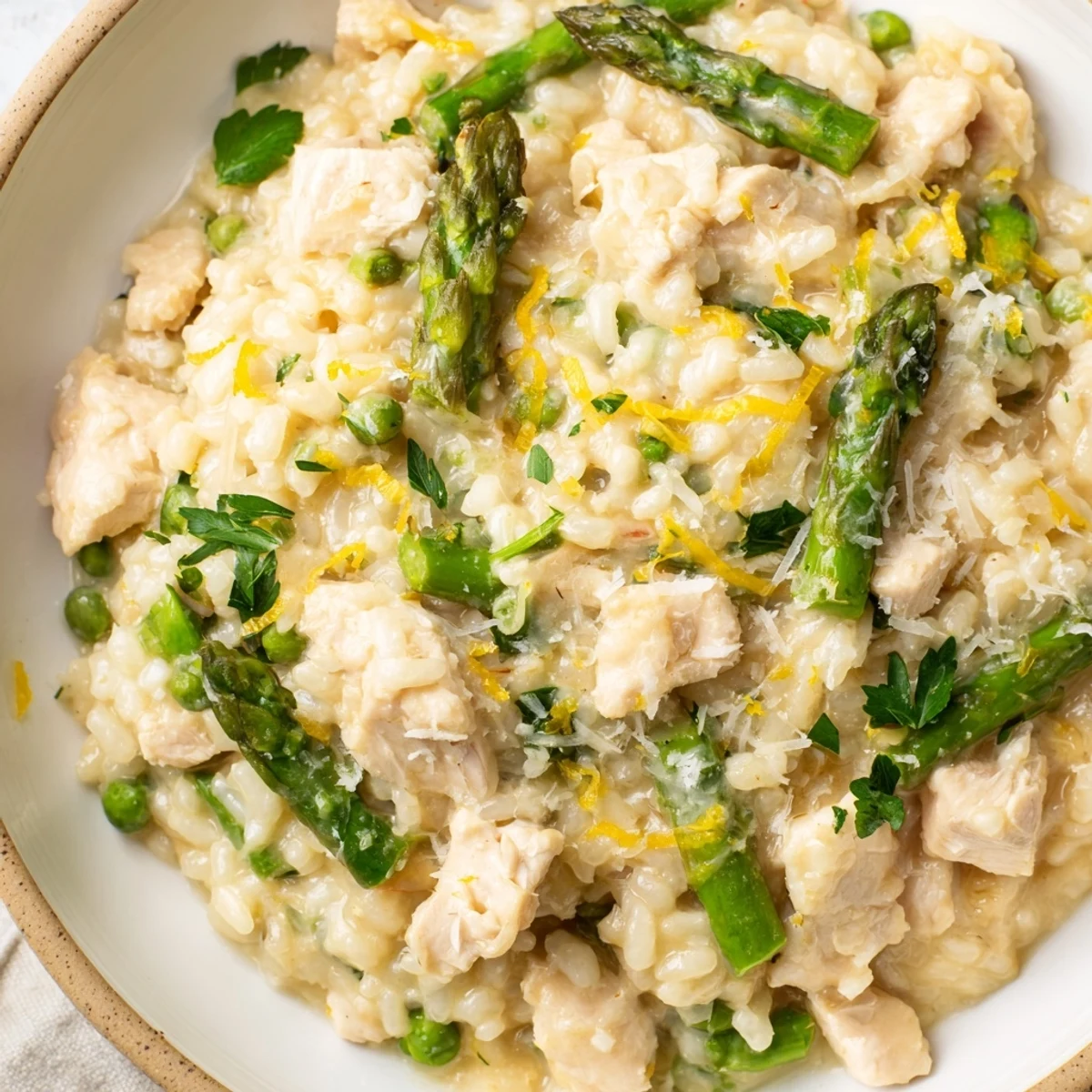 Savory Italian chicken and asparagus risotto garnished with lemon zest and extra cheese