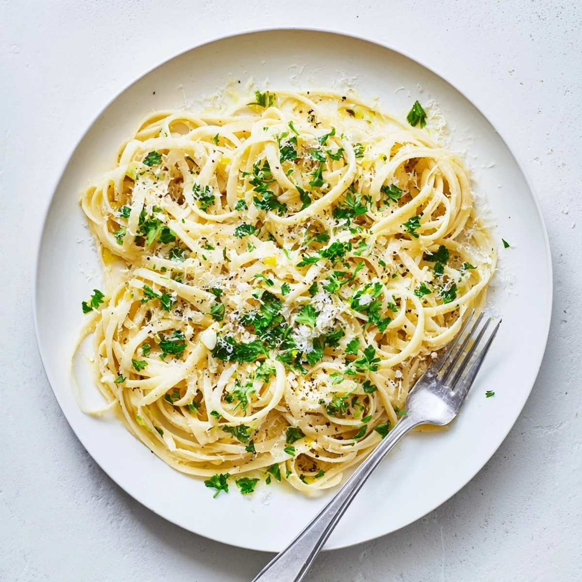 Golden strands of garlic butter pasta glisten with melted butter and fresh parsley