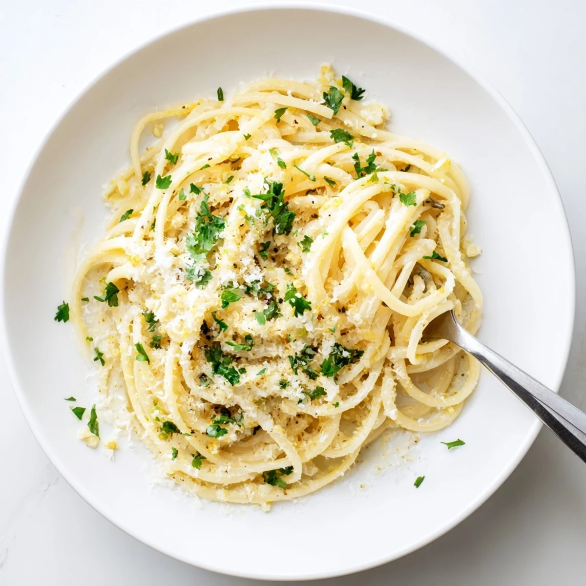 Steaming plate of garlic butter pasta tossed with lemon and Parmesan cheese
