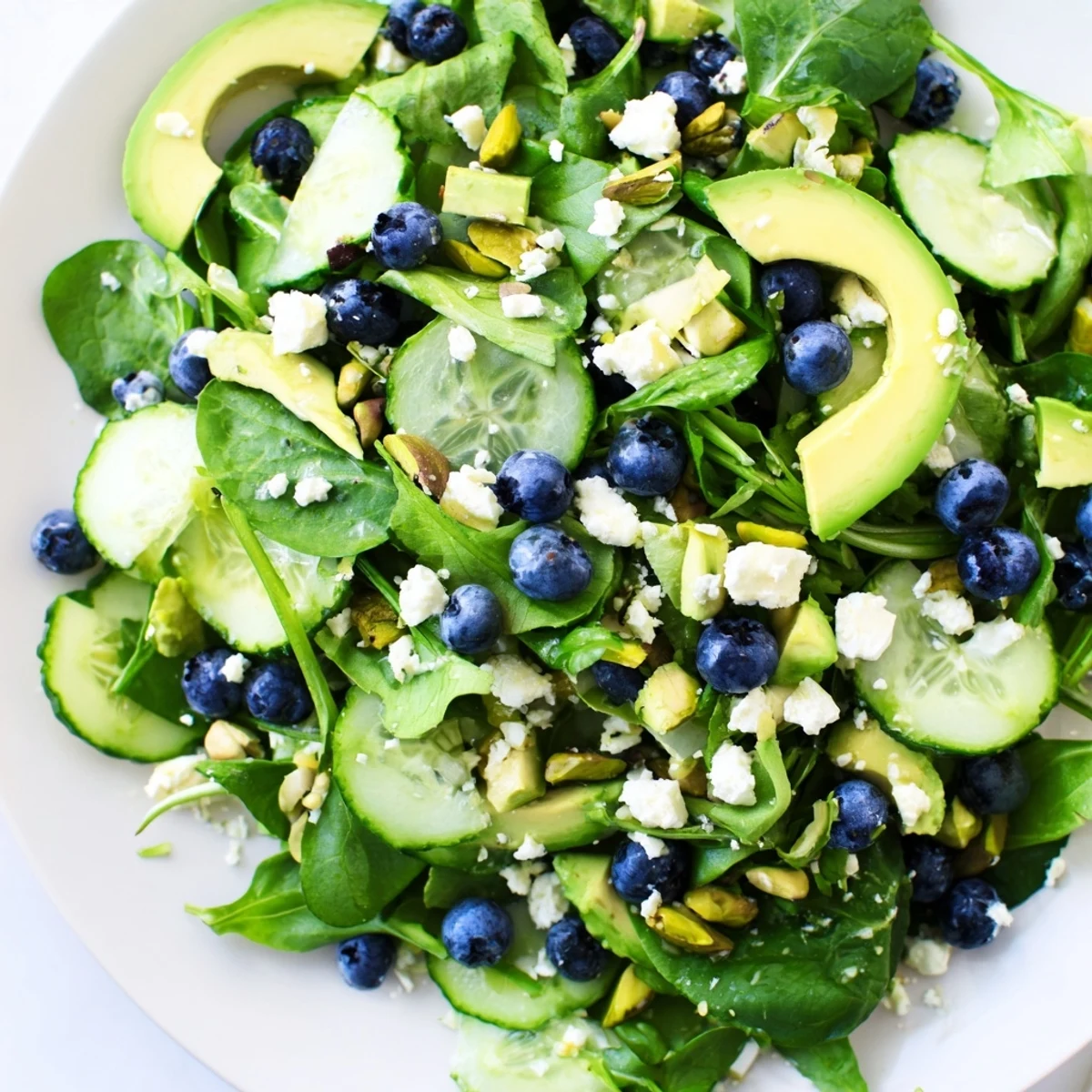 A vibrant blueberry pistachio spring salad with feta cheese on a rustic wooden board