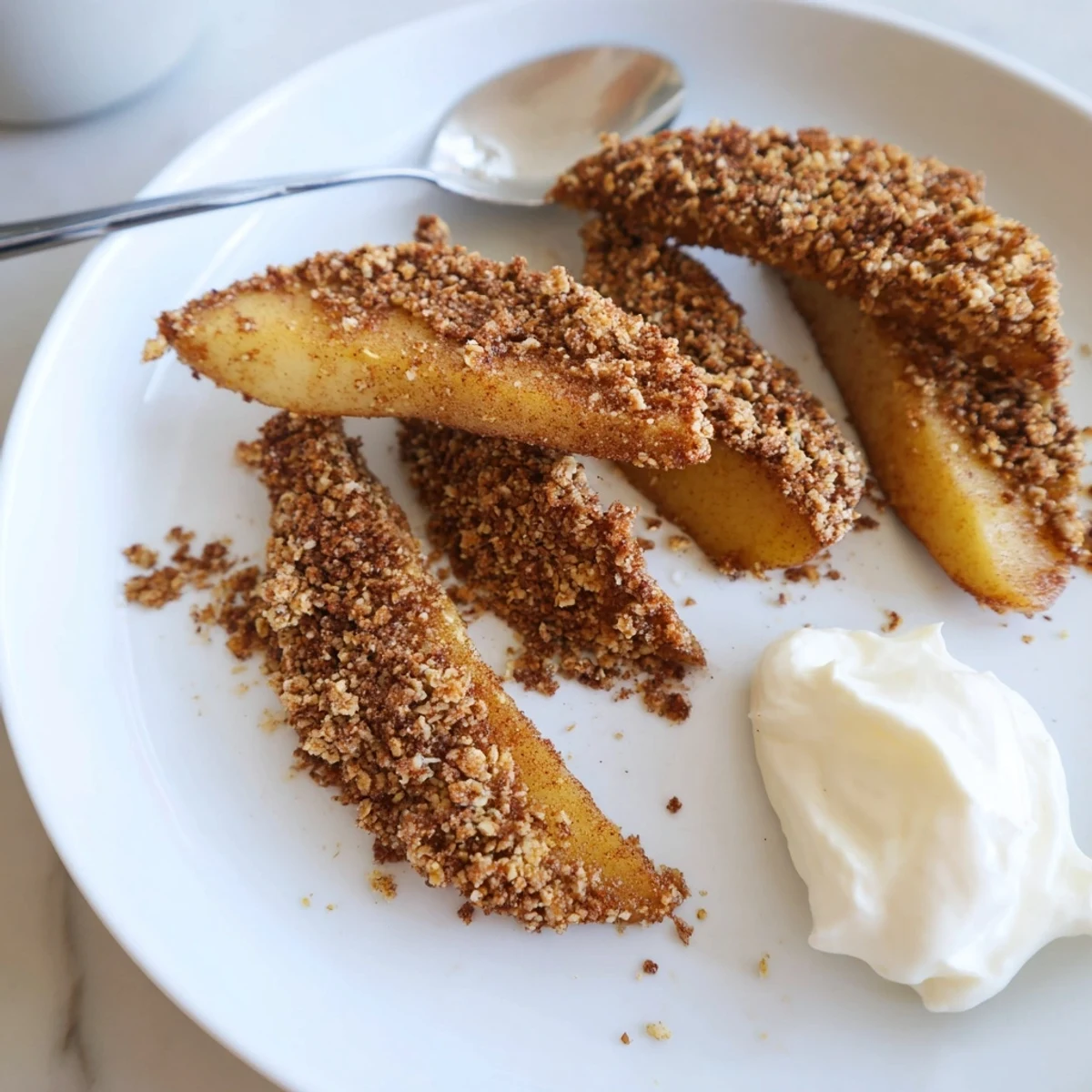 Golden crispy air fryer apple slices with warm cinnamon sugar coating served on a white plate