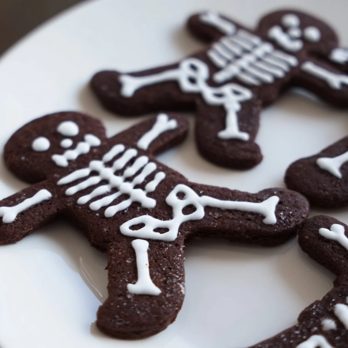 Crisp chocolate cinnamon skeleton cookies with white icing bones on a parchment-lined baking sheet