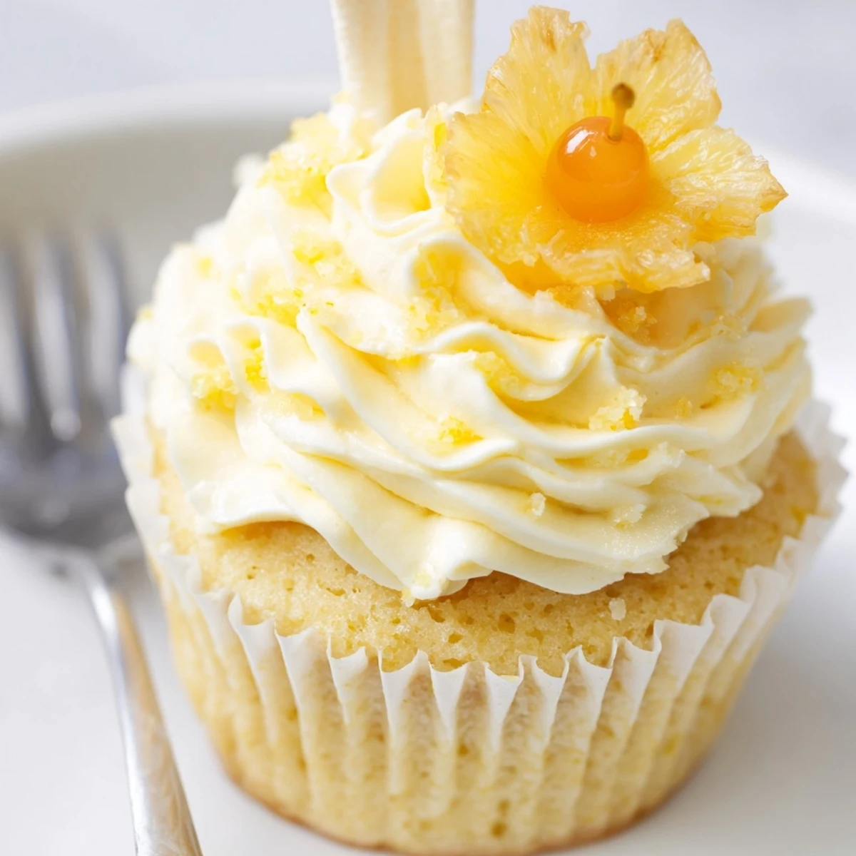 Dole Whip Cupcakes Recipe plated with maraschino cherry and dried pineapple garnish, tropical