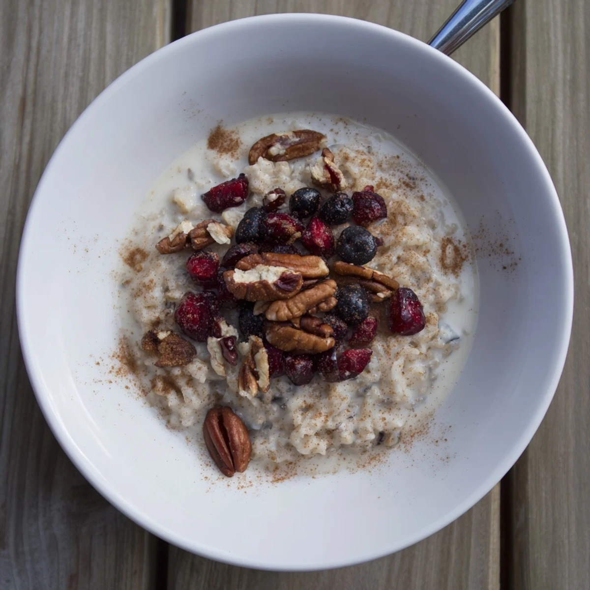 Cozy wild rice porridge served in rustic bowl with dried cranberries and milk swirl