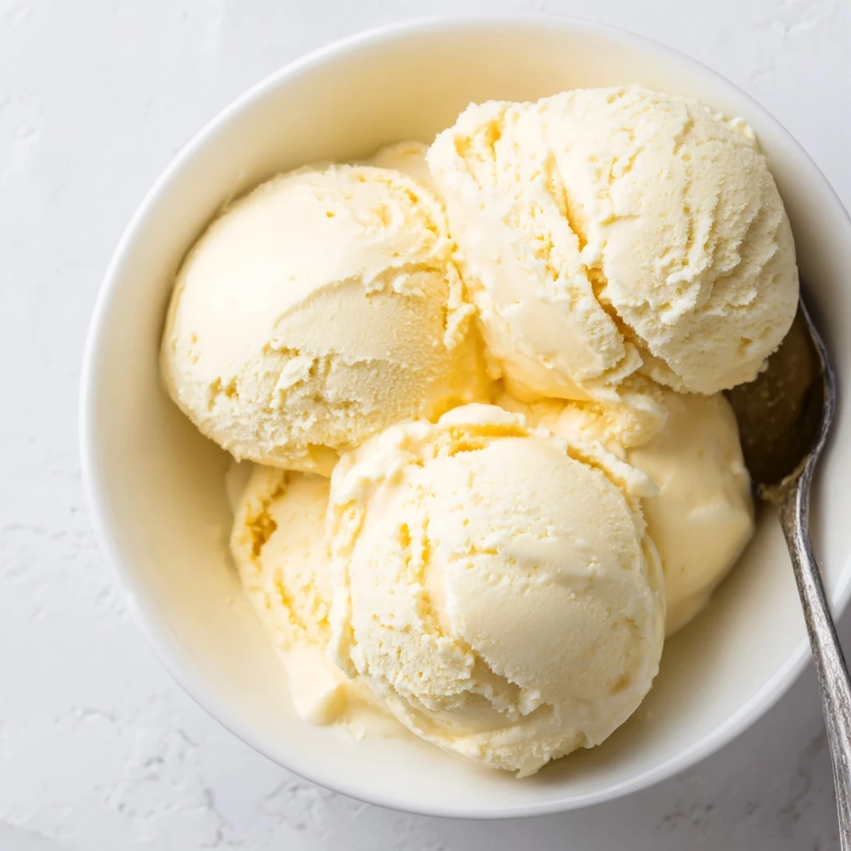 Freshly churned vanilla ice cream recipe piled high with soft melting scoops on a wooden dessert board