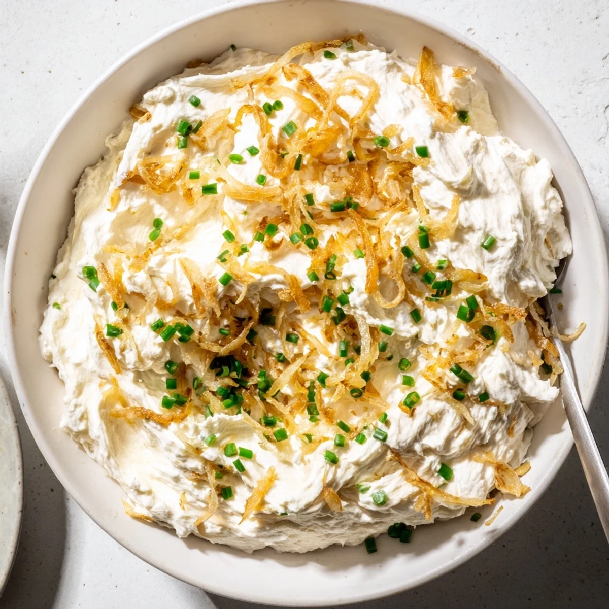 Creamy French onion dip topped with caramelized onions and fresh chives garnish