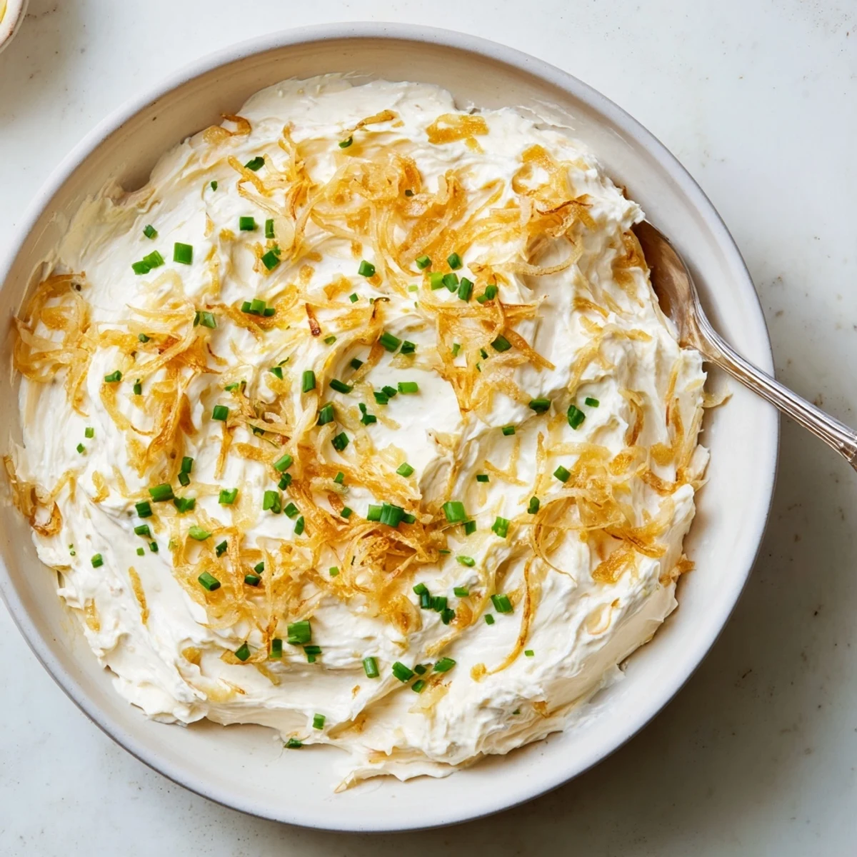 Golden brown caramelized onions folded into rich French onion dip in serving bowl