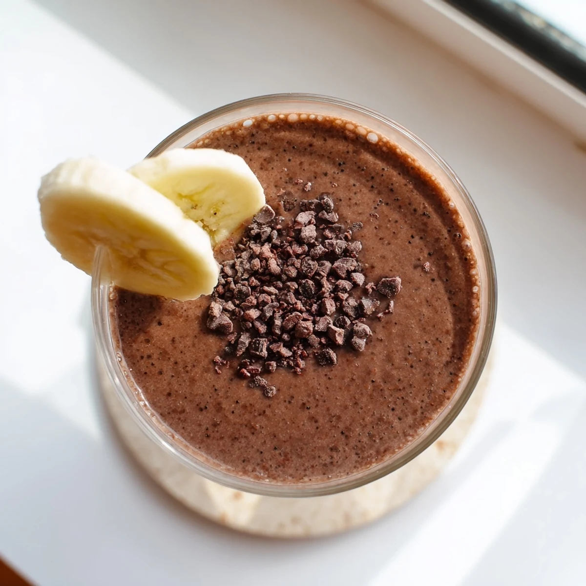 Vegan raw chocolate banana shake topped with cacao nibs and cinnamon dusting