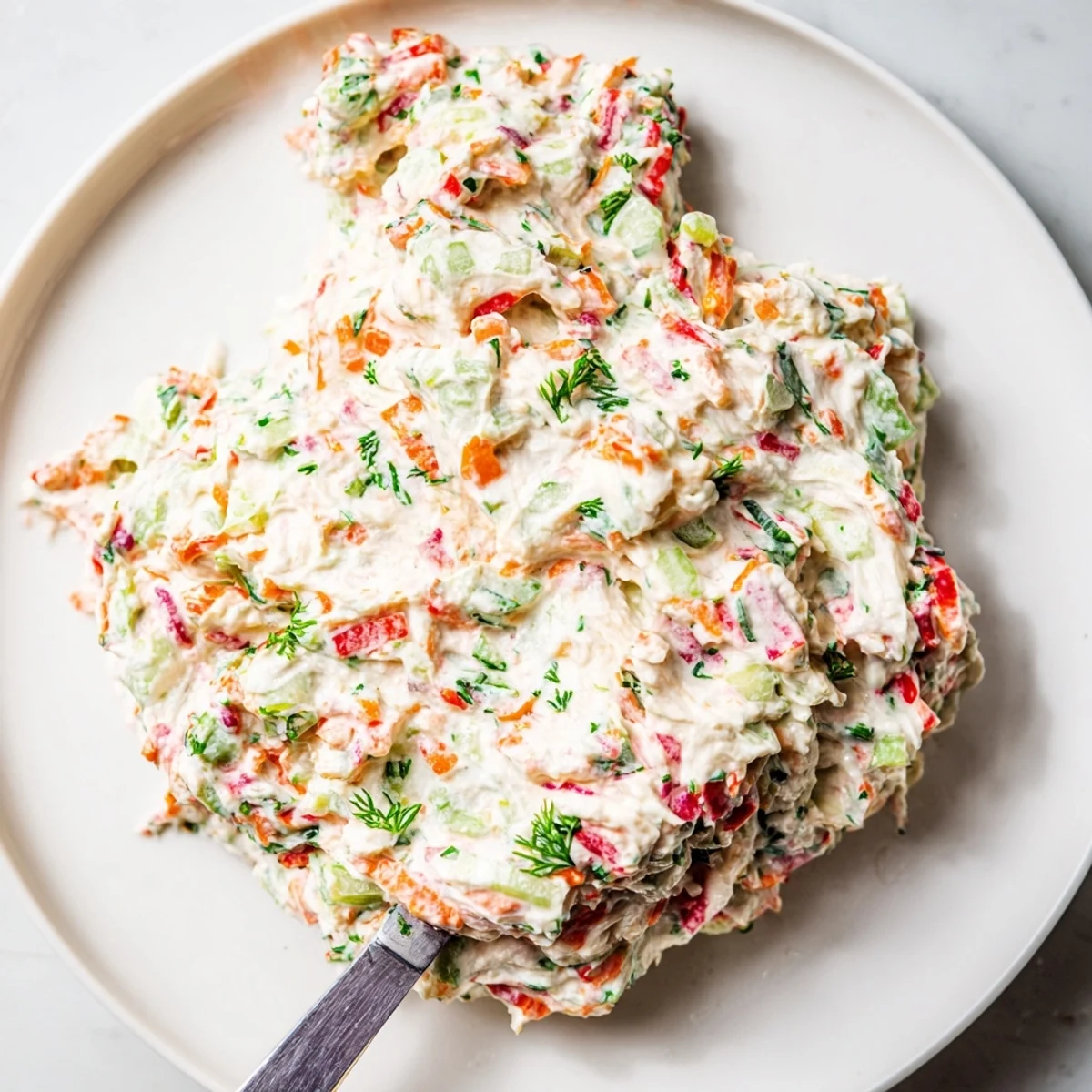 Garden vegetable spread in a white bowl surrounded by fresh cucumber and bell pepper slices