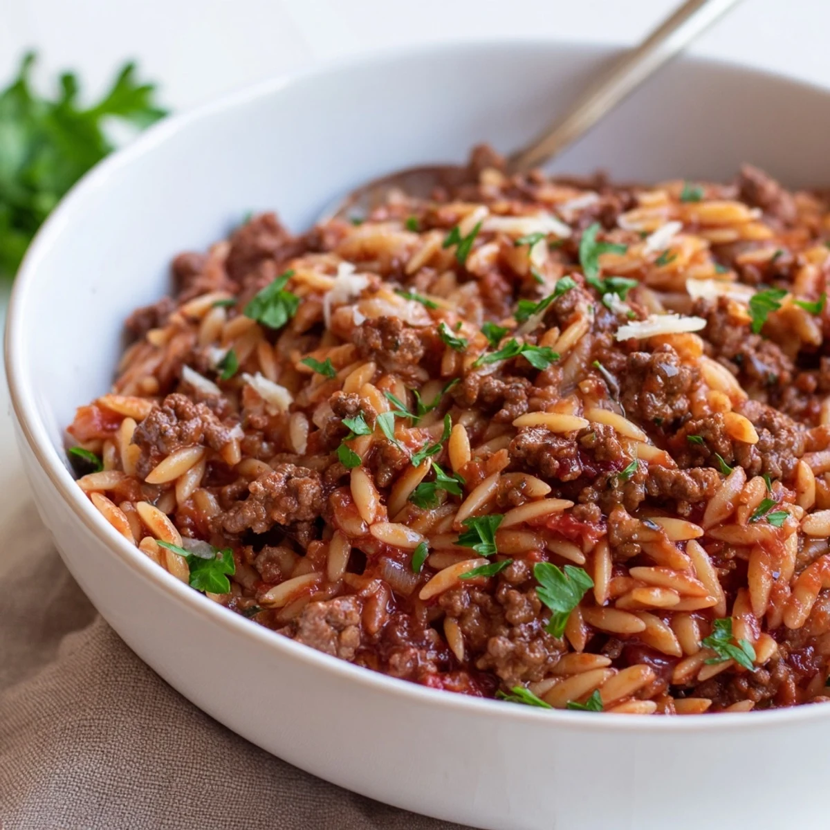 Ground Beef Orzo Greek Manestra simmering in pot, tomato aroma, parsley garnish