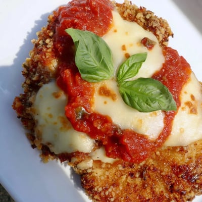 Fresh basil leaves garnish this homemade Chicken Parmesan Pizza, sliced and ready to serve.