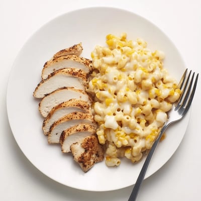 Close-up of golden seared chicken drizzled with sweet and spicy honey pepper sauce, paired with a bowl of cheesy macaroni for the Sweet and Spicy Honey Pepper Chicken with Creamy Mac and Cheese.