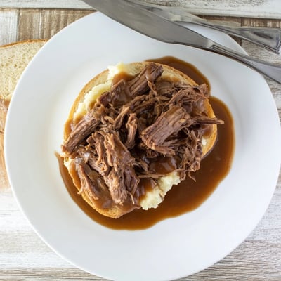 Hearty Slow Cooker Beef Manhattan featuring juicy shredded beef, buttery mashed potatoes, and savory gravy, ready for a comforting family dinner.